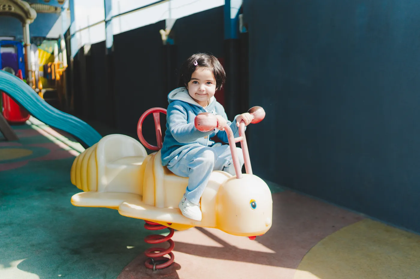 A girl riding a spring rocker in the play area