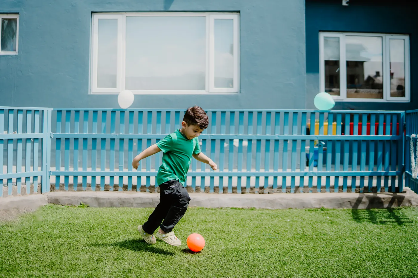 A boy playing football on the grass outside