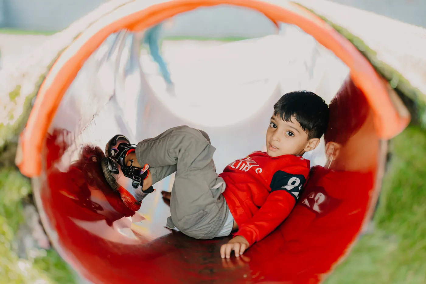 A boy crawling through a colourful play tunnel