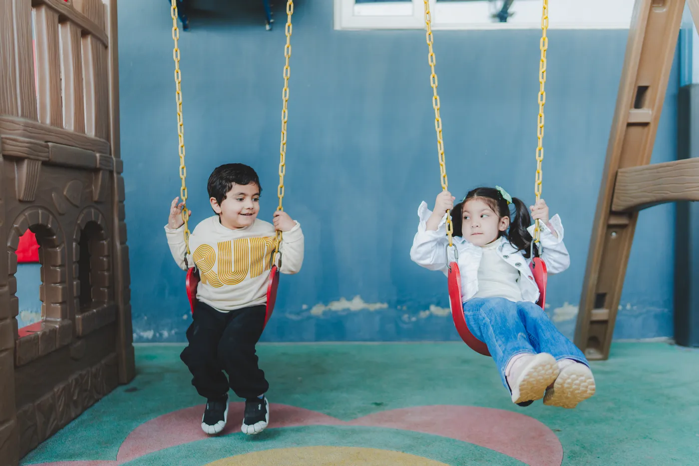 Two children swinging side by side in the play area