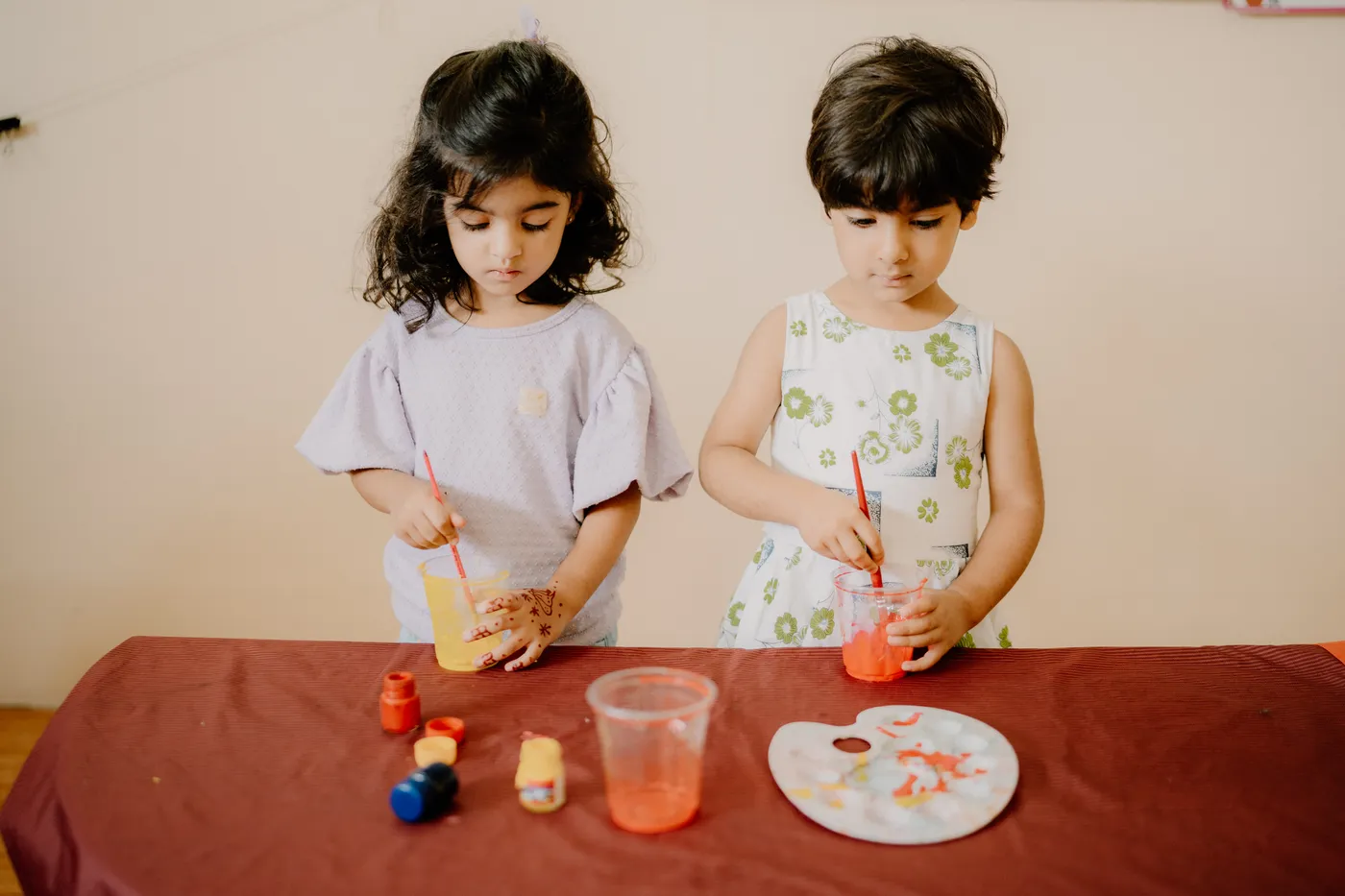 Two girls painting with brushes at the art table