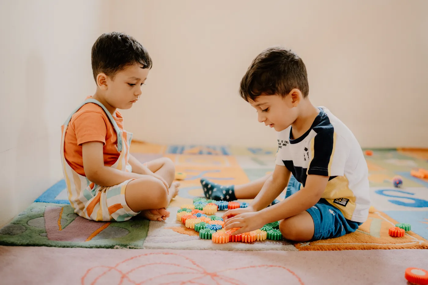 Two boys building with colourful construction toys on the rug