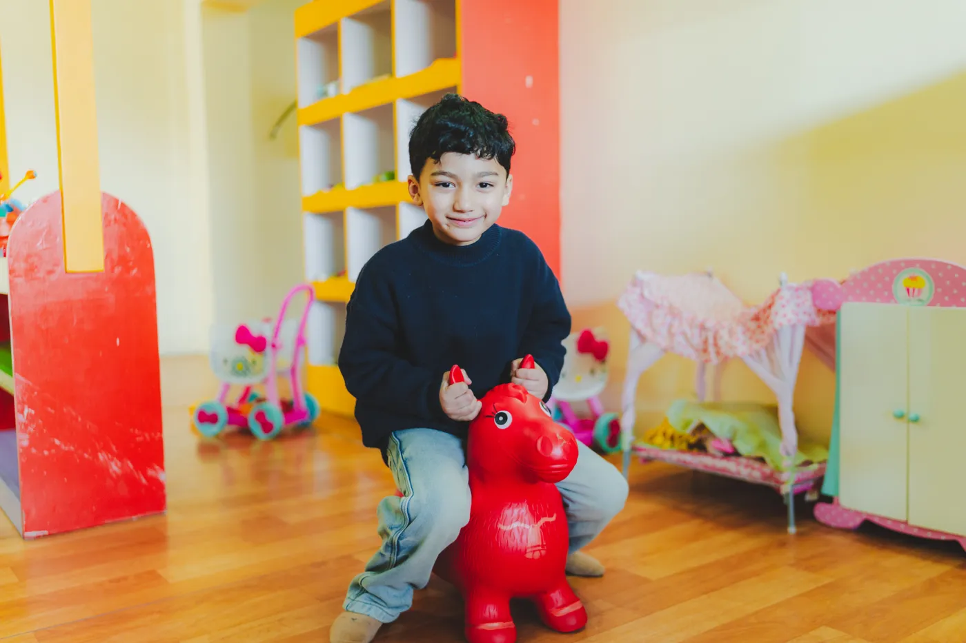 A boy riding a red bouncy ride-on horse